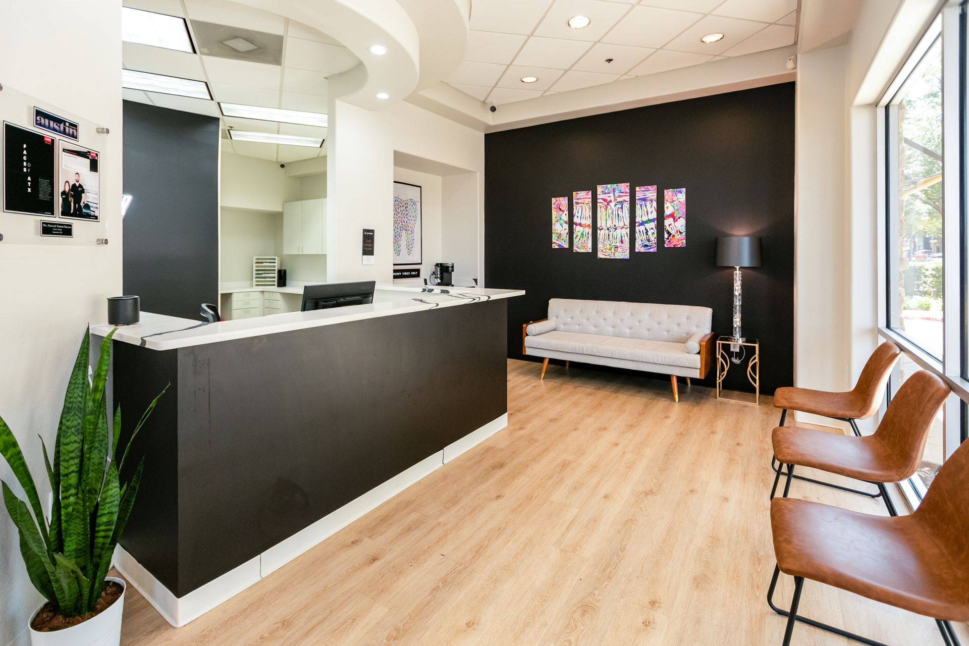 Modern clinic reception with black desk, white sofa, and tan chairs in a bright lobby