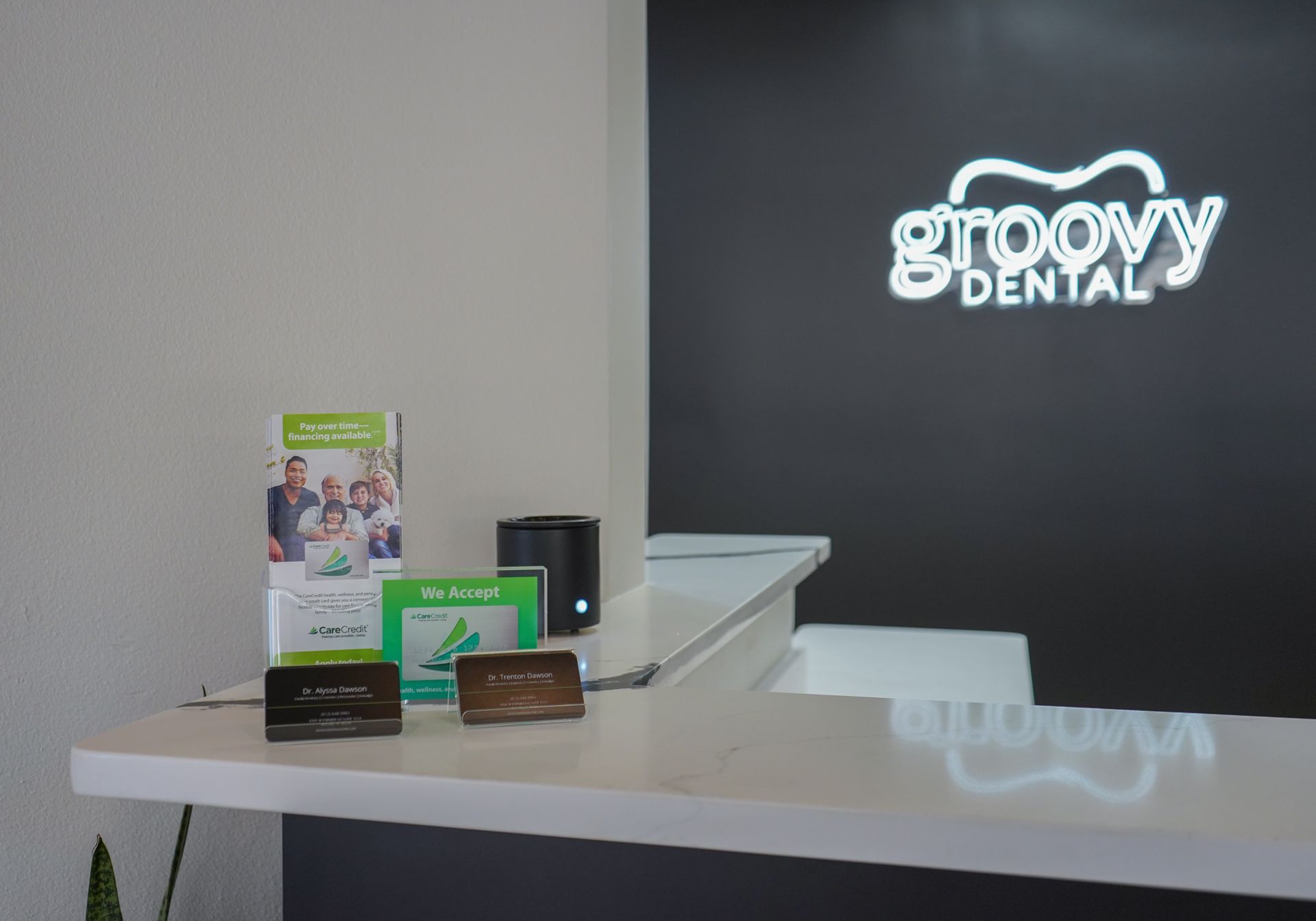 Reception desk with dental brochures and Groovy Dental sign on a black wall