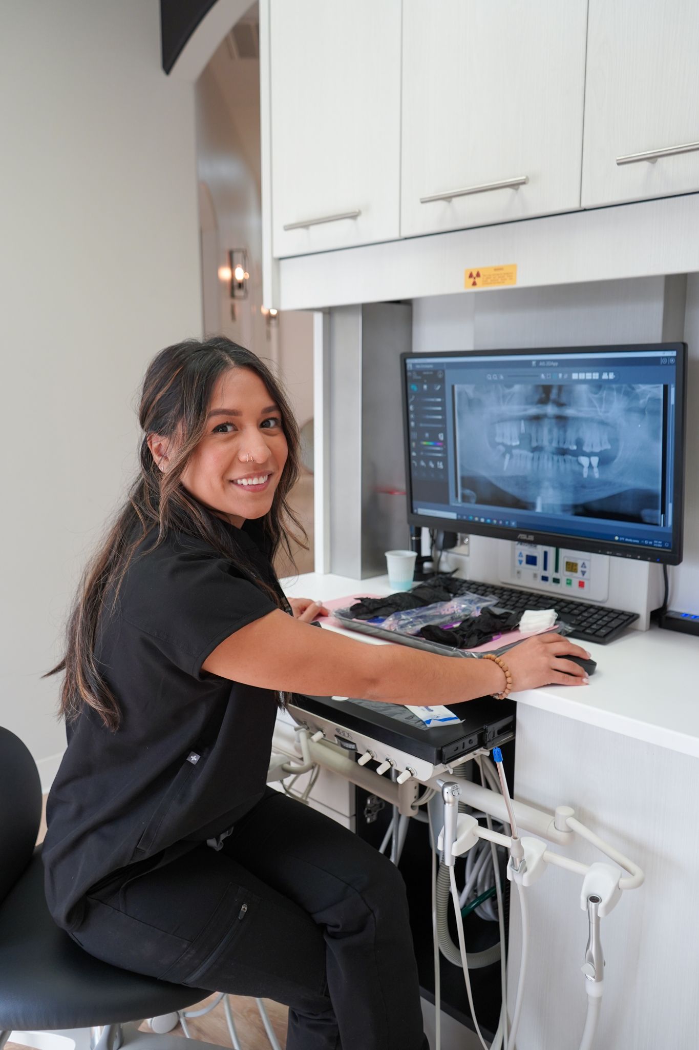 Person smiling at a workstation, using a computer monitor in a bright office.