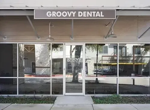 Groovy Dental storefront with glass windows and a central entrance under a striped awning