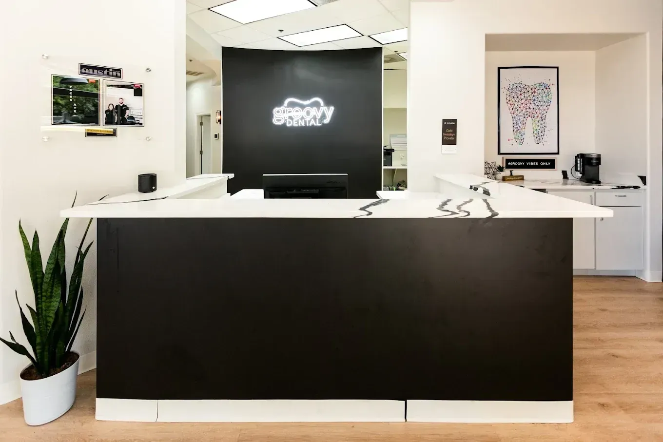 Modern office reception desk with black front panel, white counters, potted plant, and logo sign on back wall