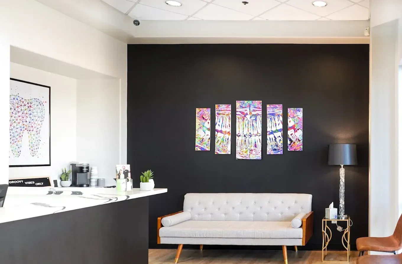 Modern office lobby with a black accent wall, colorful art, and a white sofa with a floor lamp.