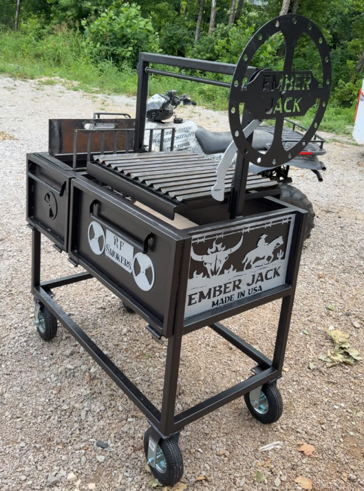 Black metal Ember Jack grill with a large wheel, on wheels, outdoors.