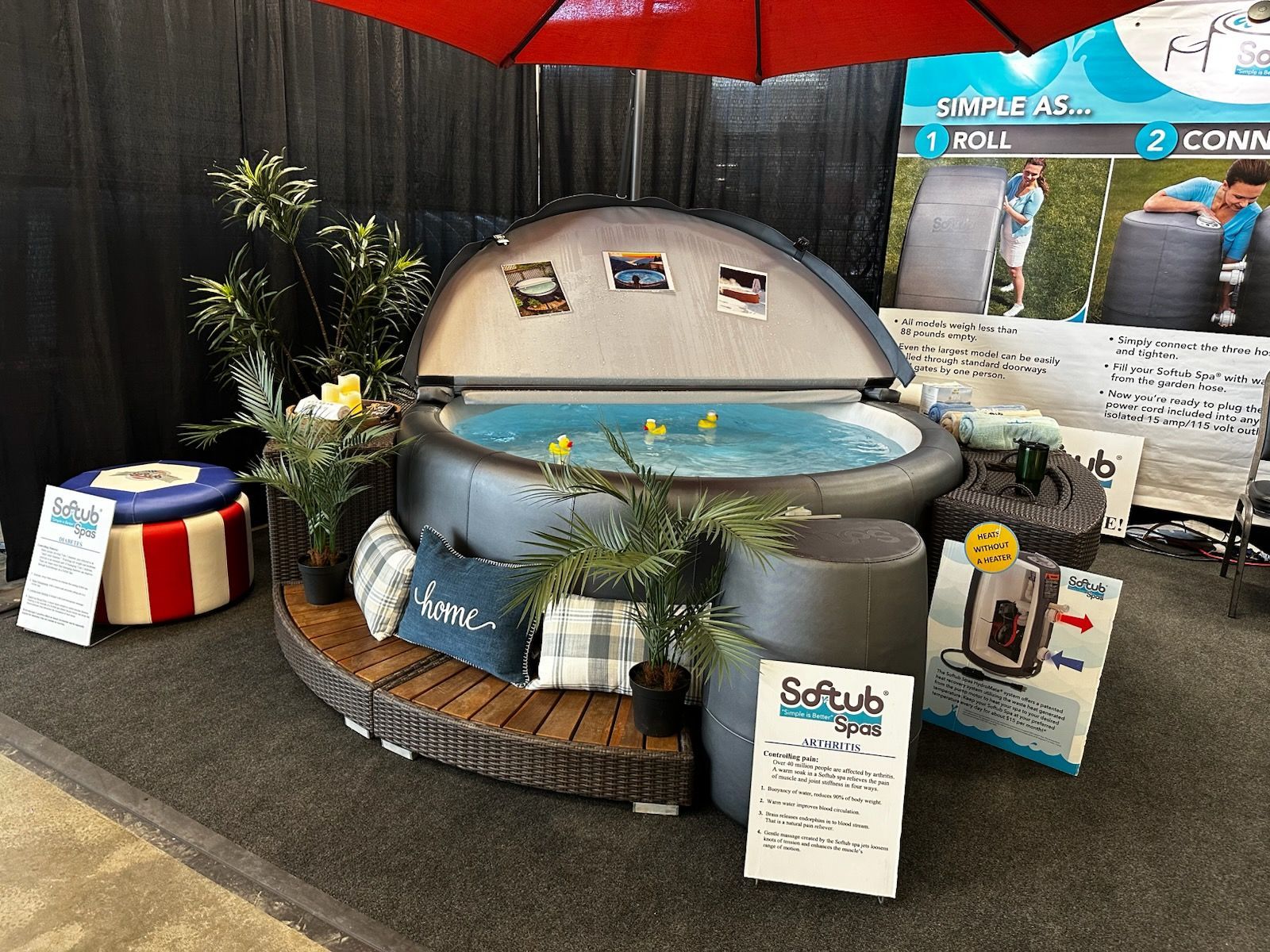 Hot tub display with plants, pillows, and product information at an event.