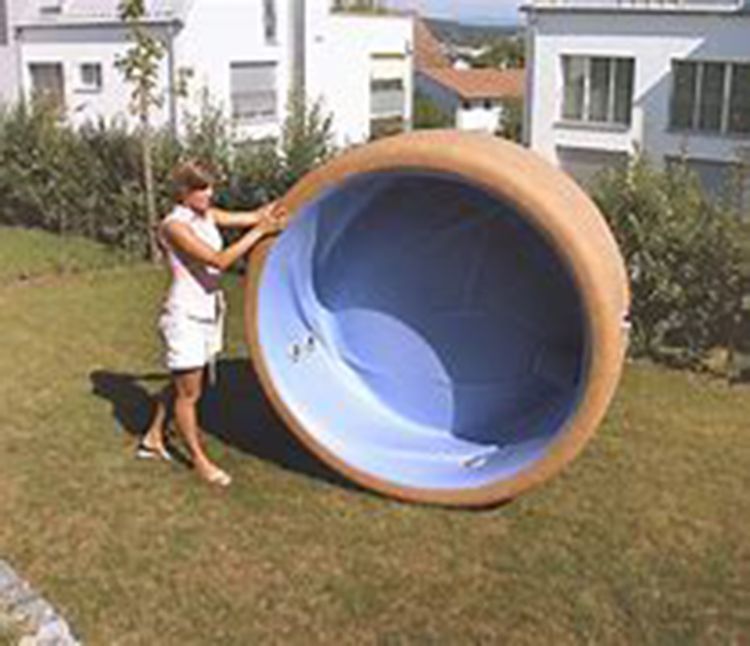 Woman holding inflatable hot tub outdoors on a lawn.