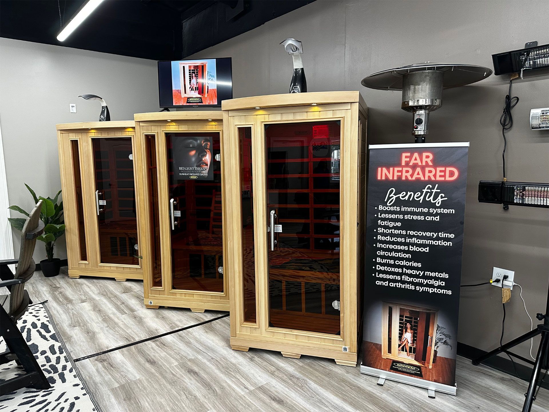 Three wooden far-infrared saunas in a shop, with a promotional banner.