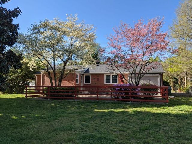 Brick house with a red fence and blooming trees on a sunny lawn