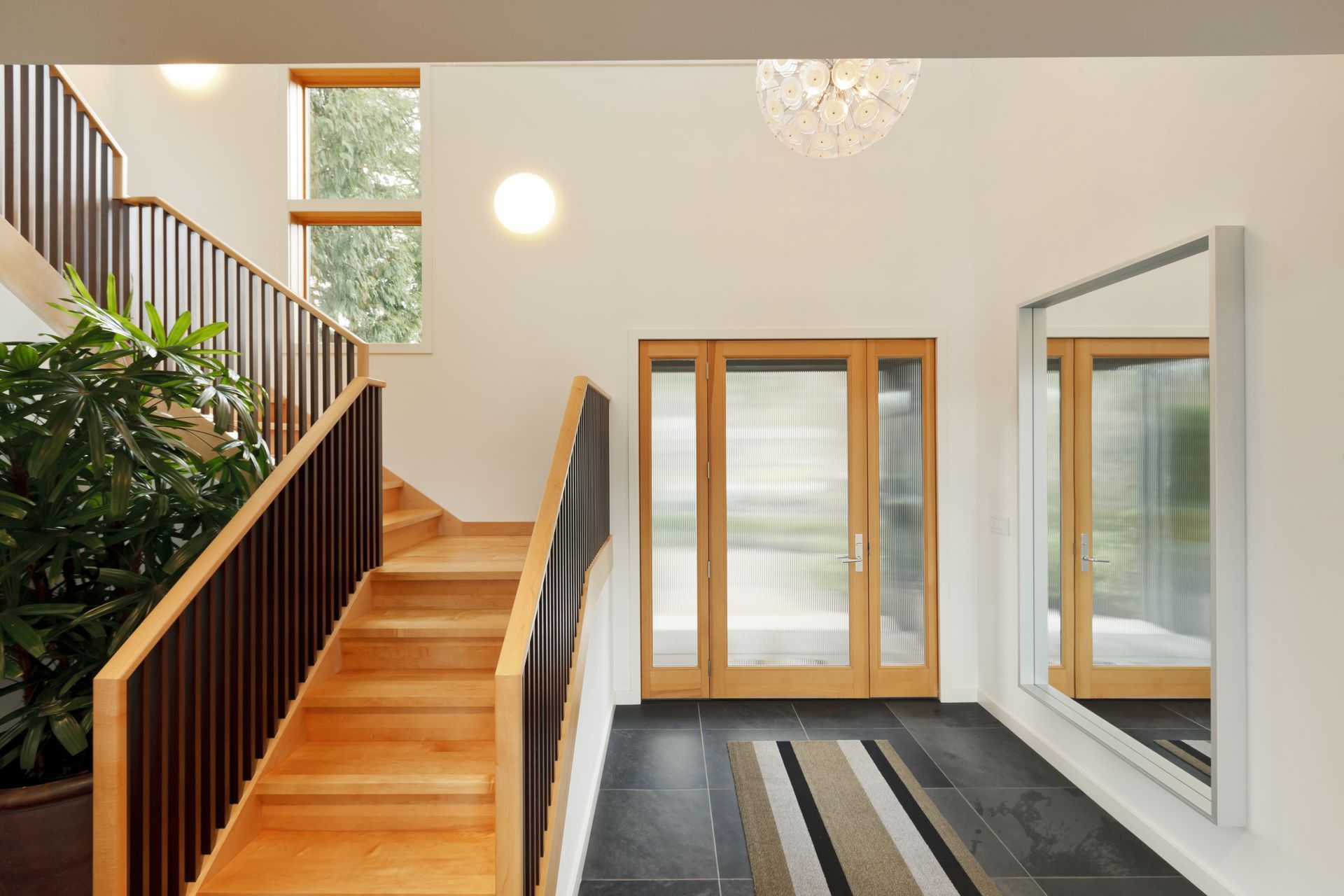 A hallway with stairs and a large mirror