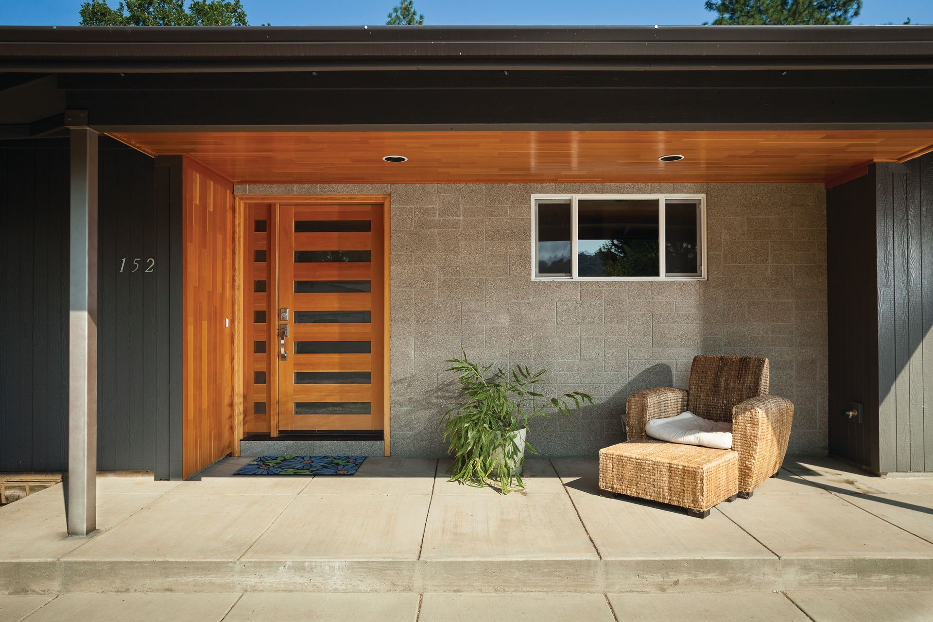A house with a wooden door and a wicker chair on the porch