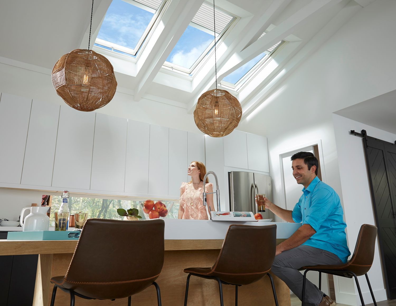 A man is sitting at a counter in a kitchen with a woman standing behind him.
