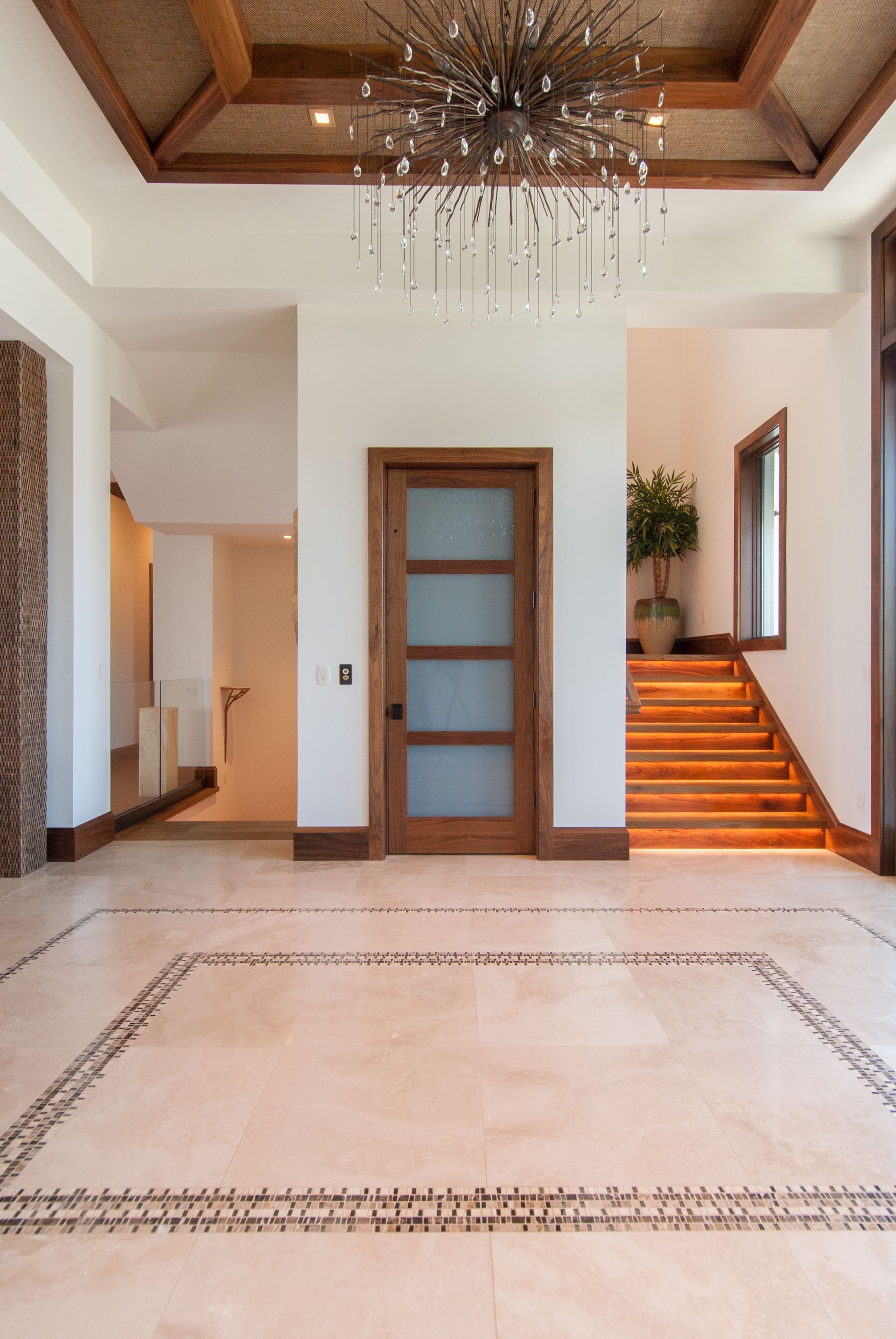 There is a chandelier in the ceiling of the hallway.