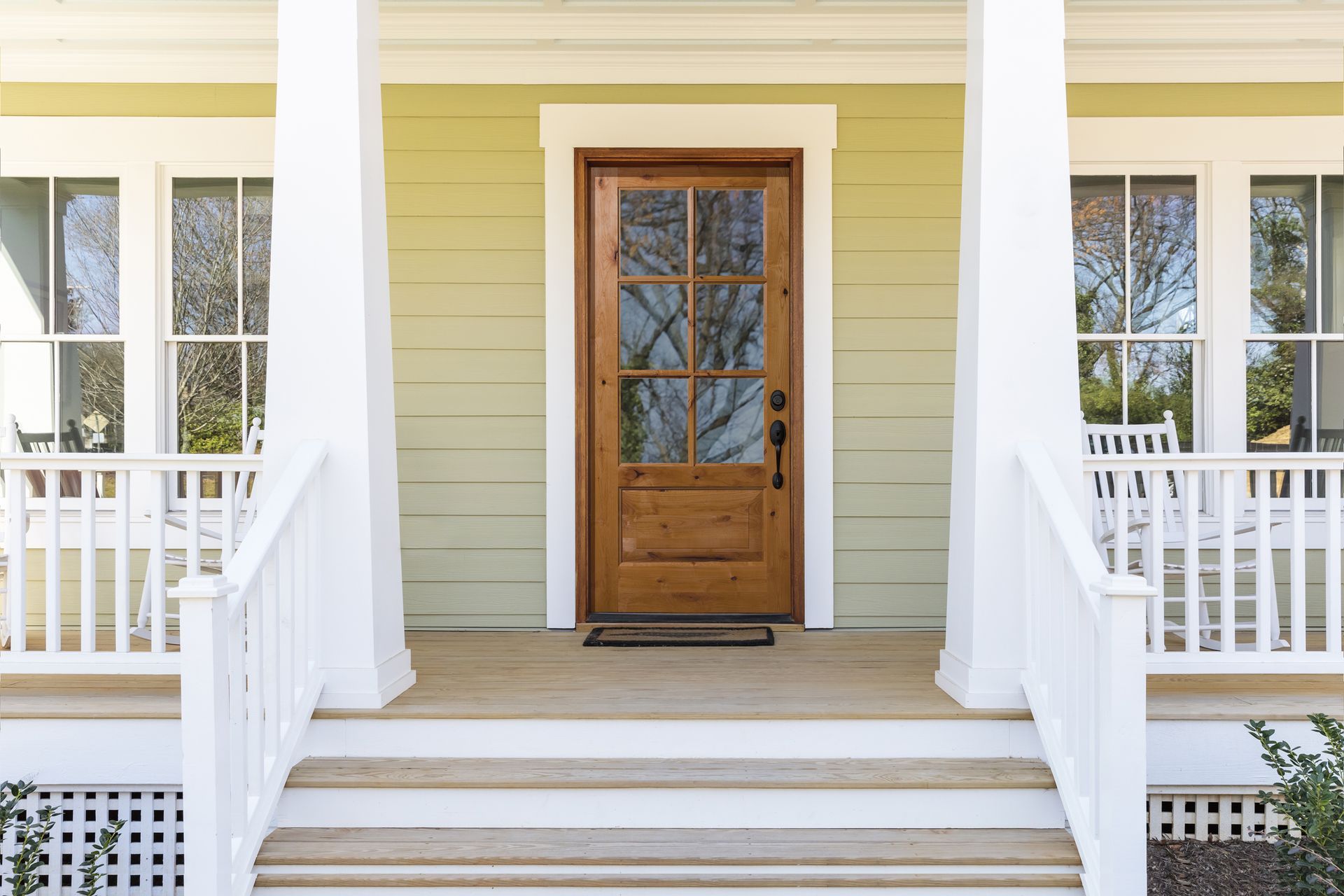The front door of a house with a porch and stairs leading to it.