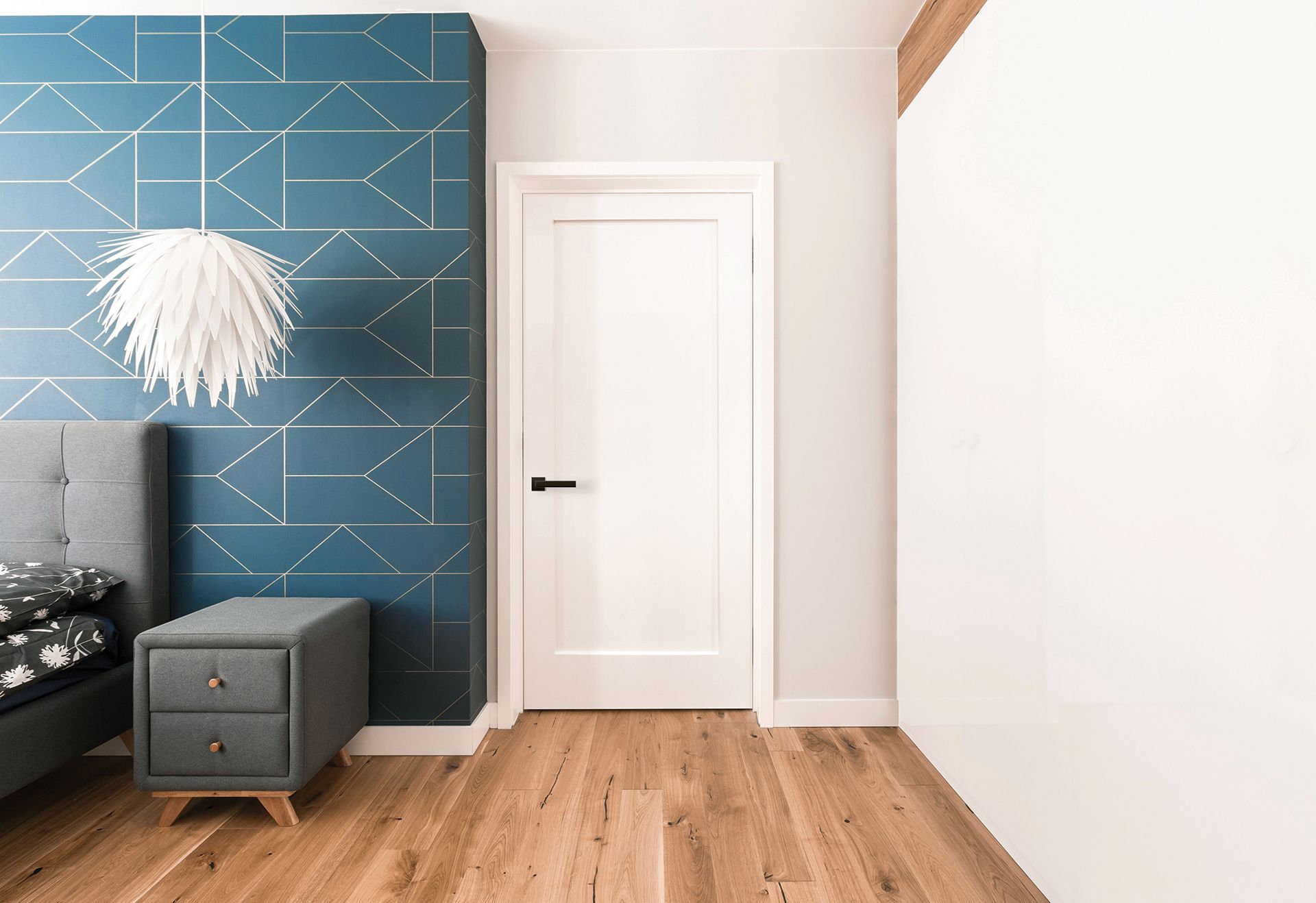 A bedroom with a bed, nightstand, and door.