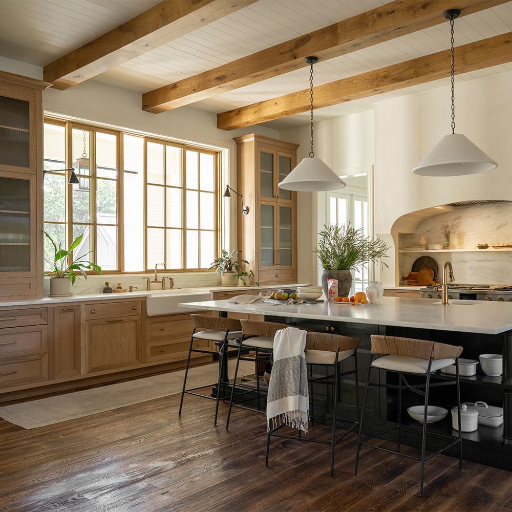 A kitchen with wooden cabinets and stools and a large island