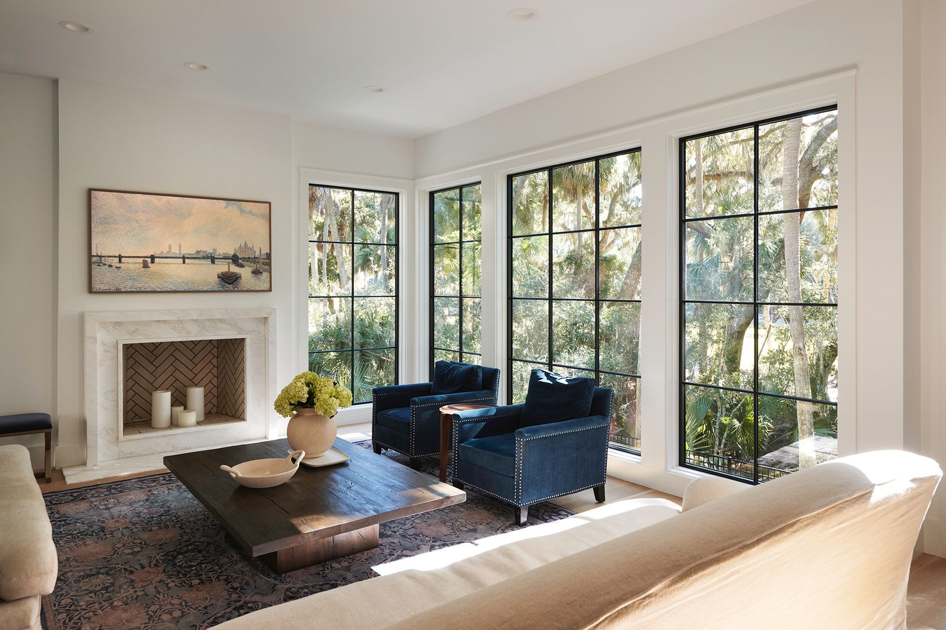 A living room with a couch, chairs, coffee table and fireplace.