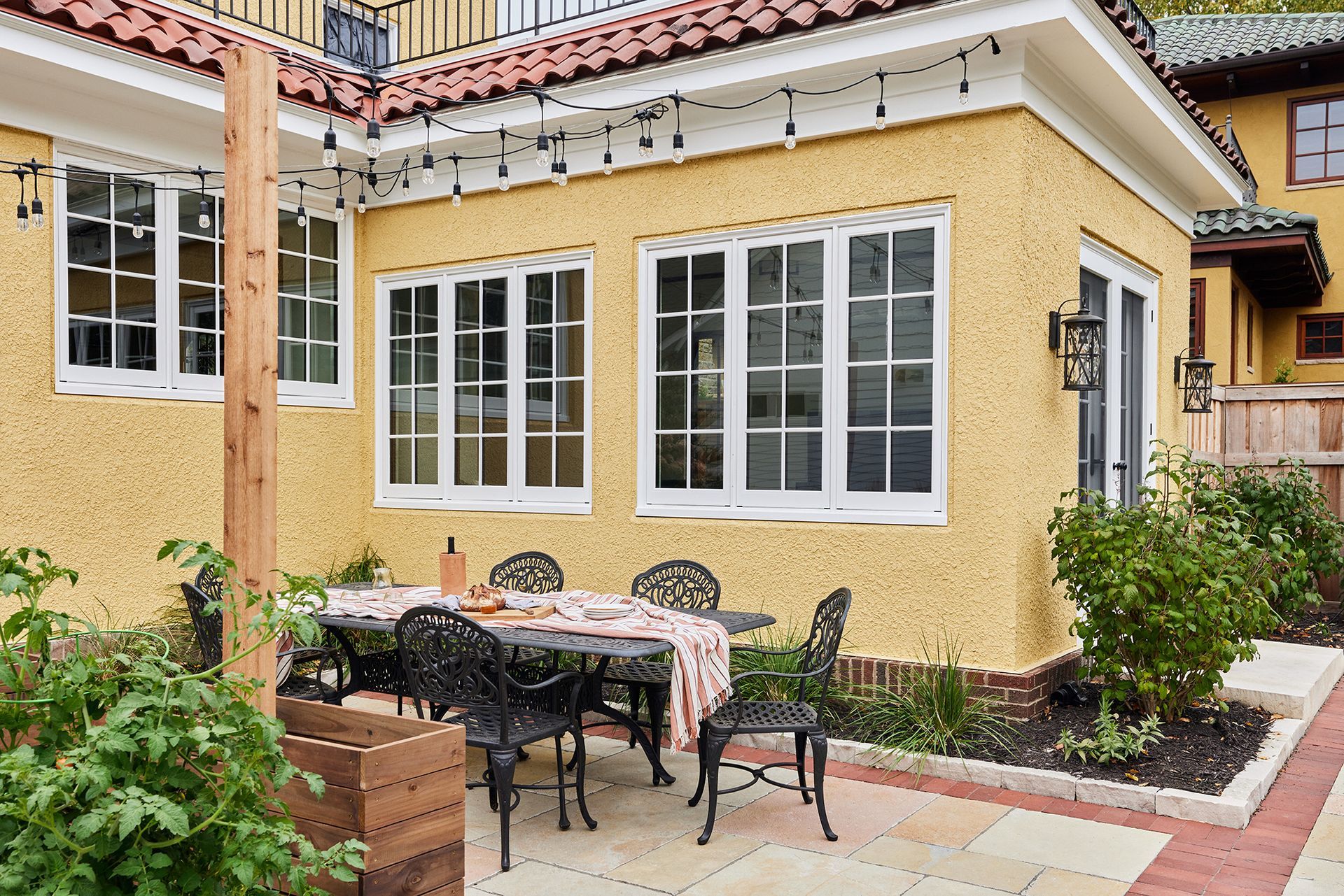 A yellow house with a patio with a table and chairs in front of it.