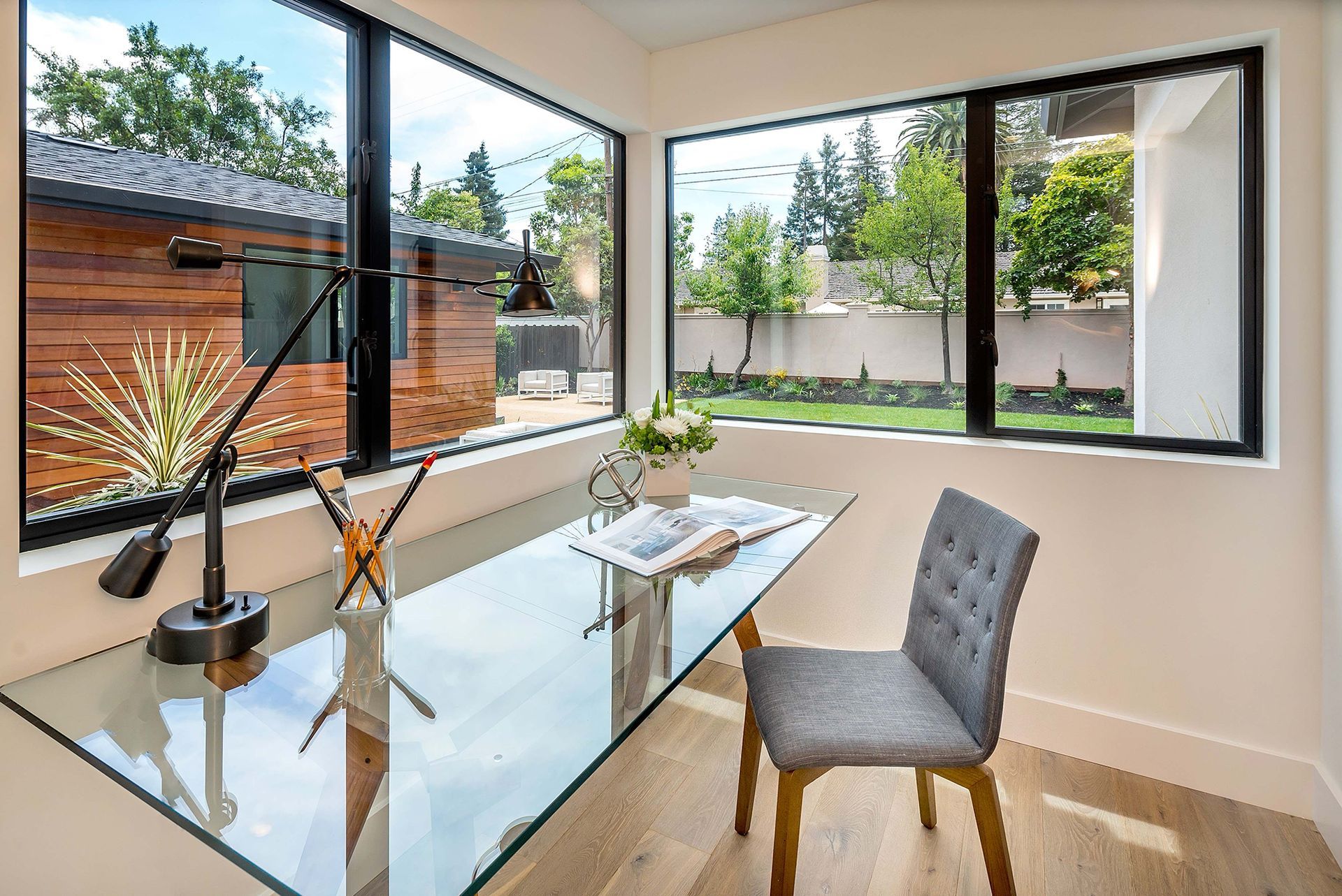 A home office with a glass desk and chair in front of a large window.
