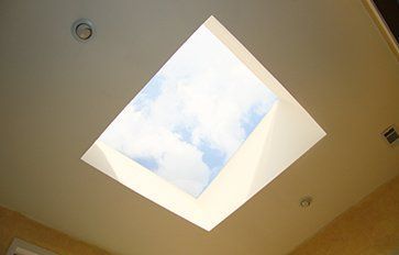 A skylight in the ceiling of a room with a view of the sky.