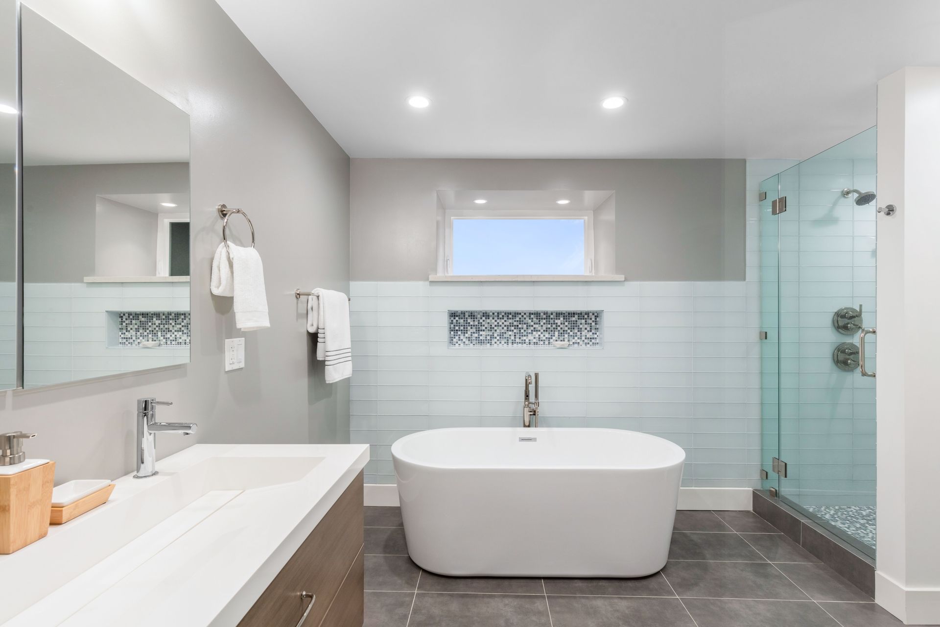 Modern bathroom with freestanding tub, glass shower, double sink, and gray tile floor