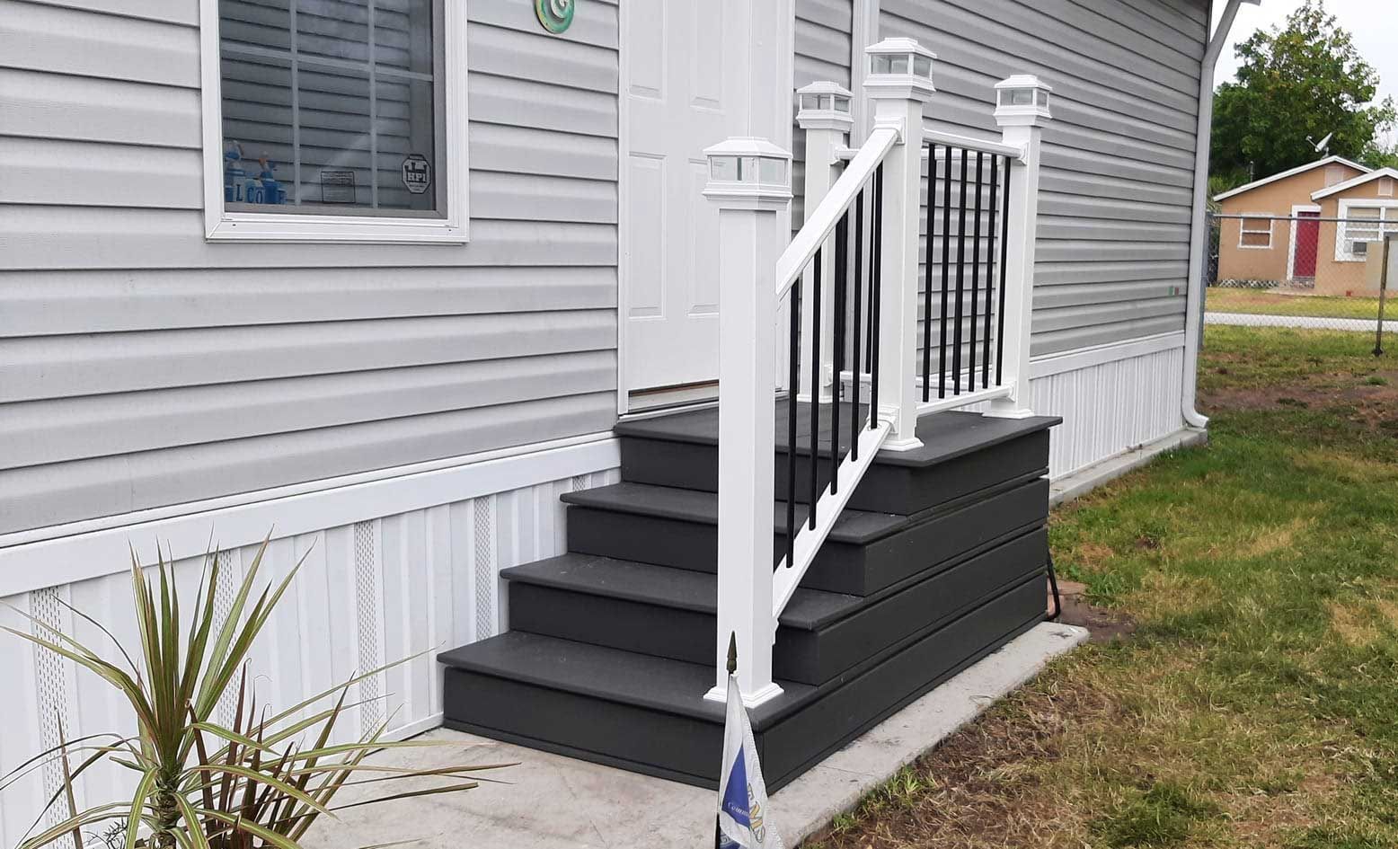 White accessibility ramp and steps with railing leading to a gray house entrance