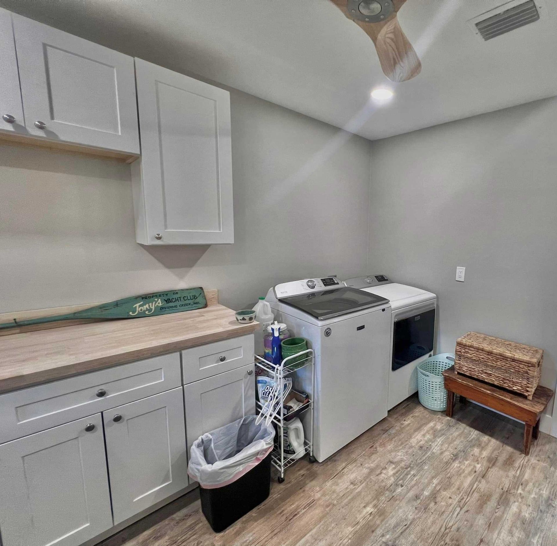Laundry room with washer, dryer, cabinets, utility sink, and a small bench in a gray-walled space