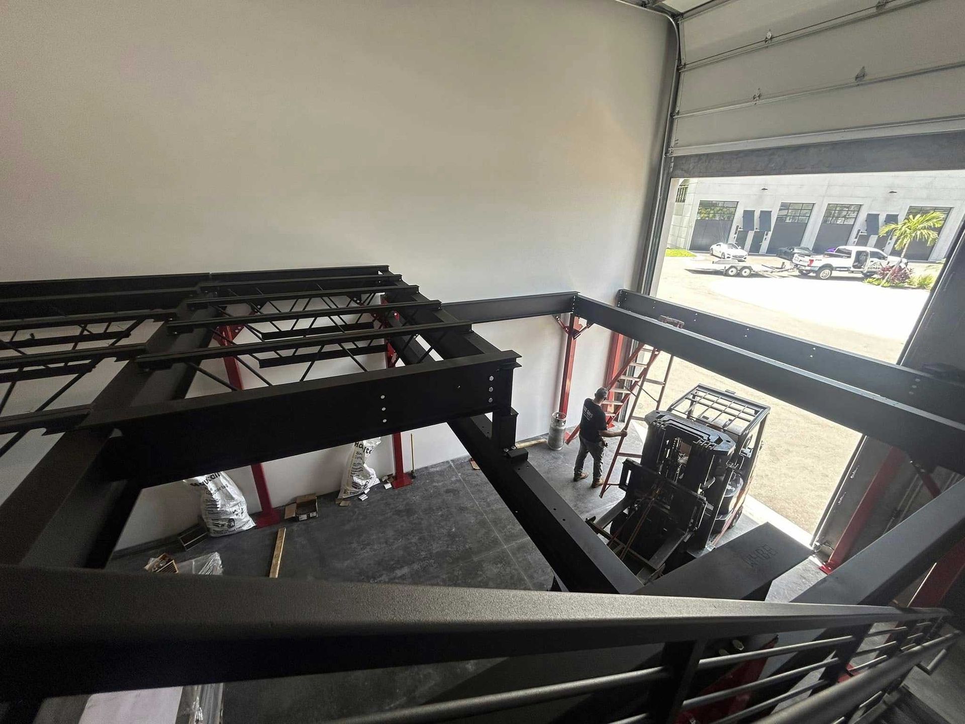 Interior of an industrial warehouse with black metal framework and an open loading bay to the right