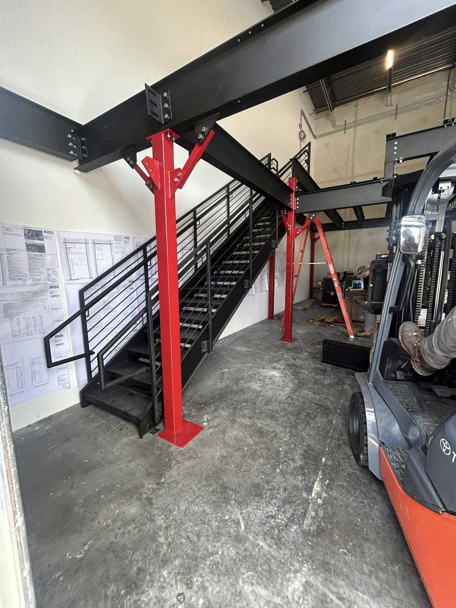 Industrial staircase with red support beams in a workshop or garage interior.
