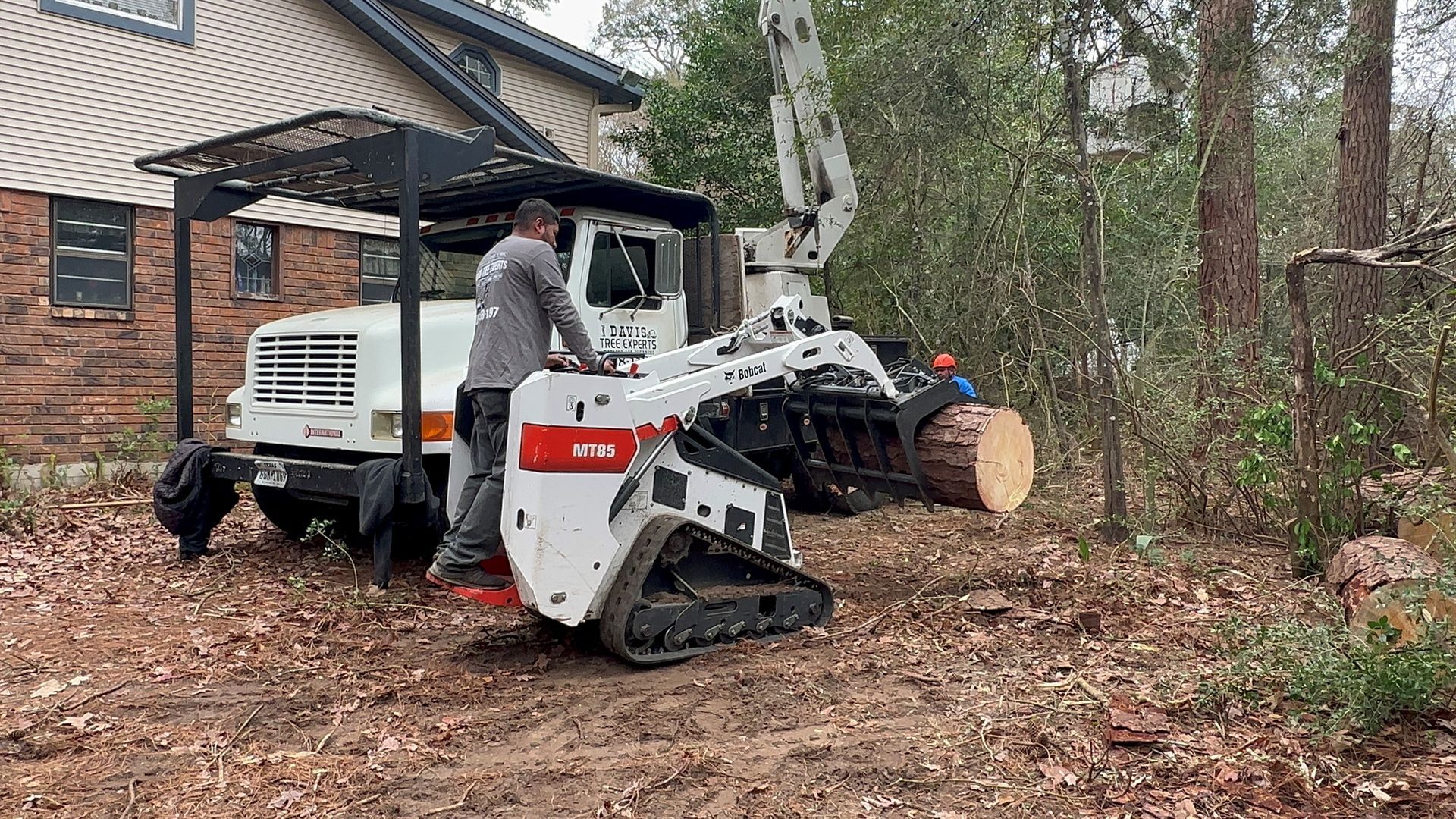 a man is standing next to a bulldozer carrying a log