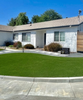 A white house with a lush green lawn in front of it