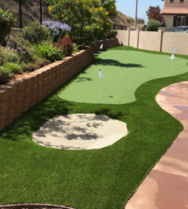 A putting green in a backyard with a brick wall