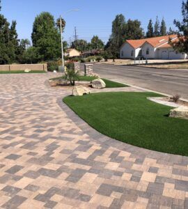 A brick driveway with a grassy area in the middle