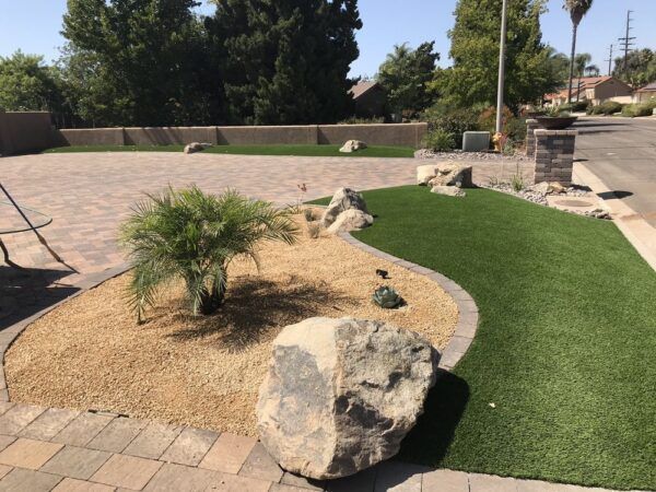 A large rock sits in the middle of a lush green lawn
