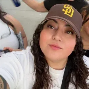 A woman wearing a san diego padres hat is taking a selfie.