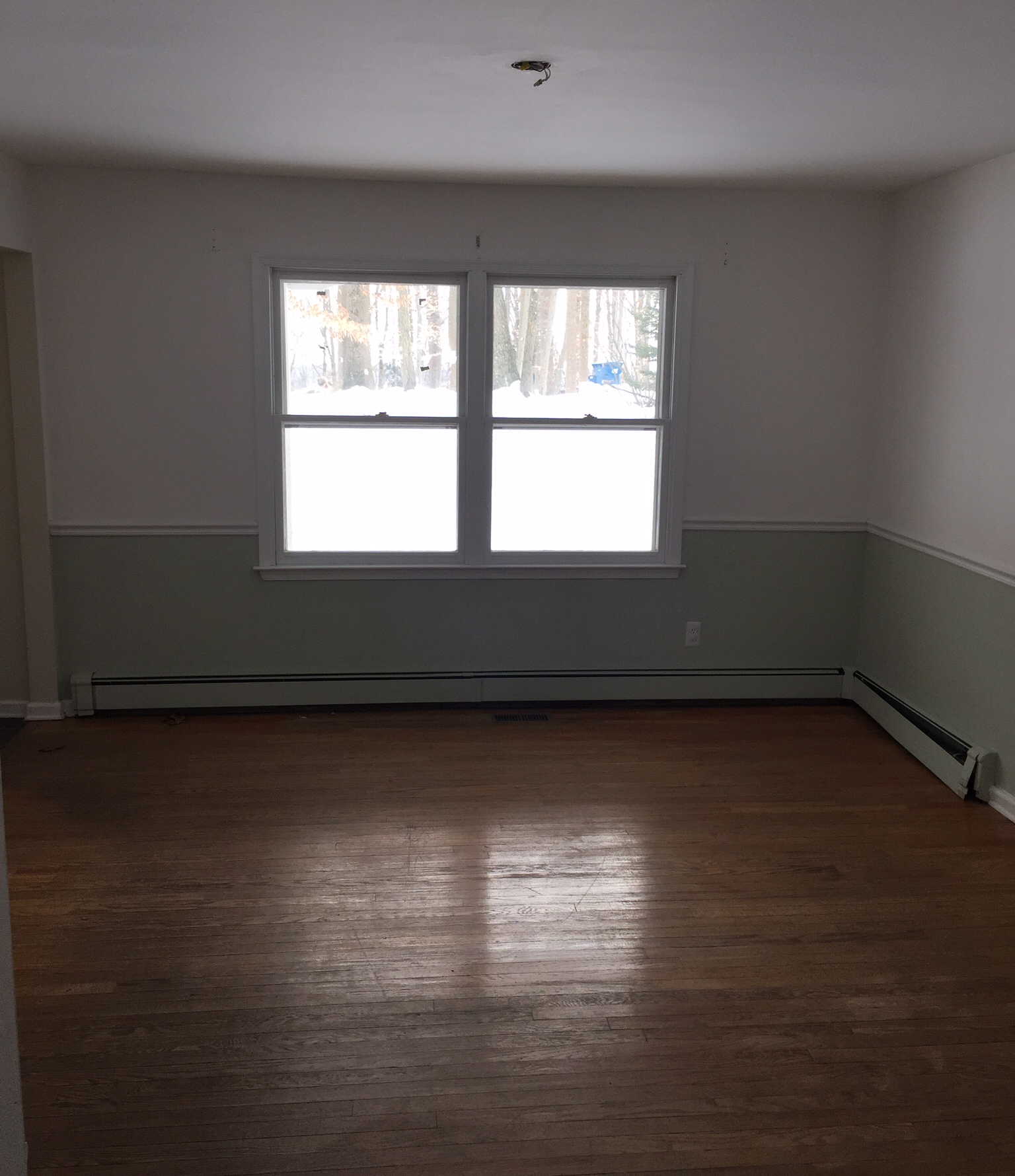 an empty living room with a large window and a wooden floor