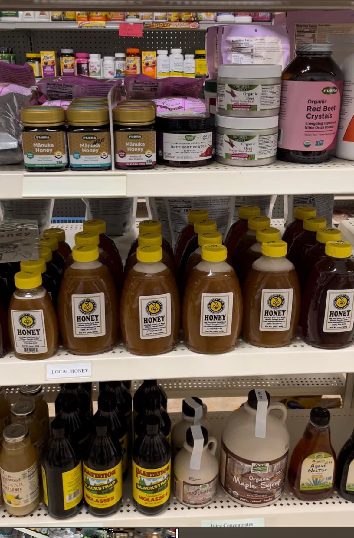 A shelf filled with bottles of honey and syrup in a store.