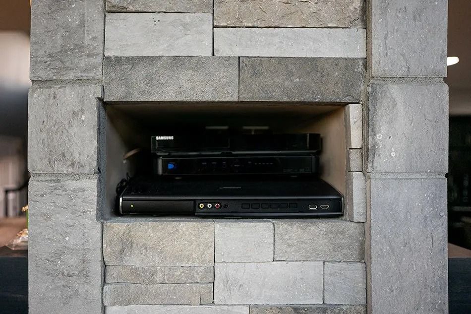 A built-in brick niche holds a stack of three black electronics components.