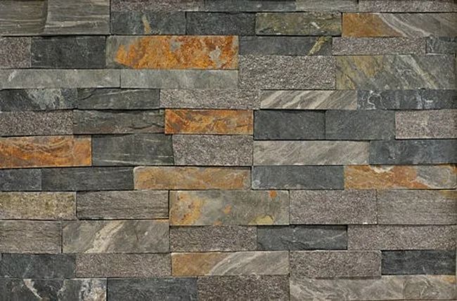 Stone wall with rectangular, multi-colored tiles in gray, orange, and brown hues.