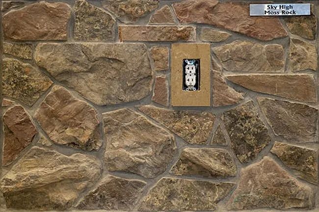 Stone wall with electrical outlet. Brown, tan, and gray stones.