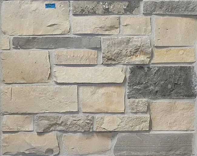 Close-up of a wall made of various sized, light-colored stone blocks, with gray and beige hues.