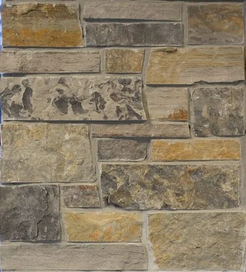 Stone wall composed of various beige, gray, and yellow rectangular and irregularly shaped pieces.