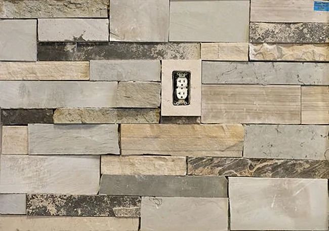 Stone tile wall with electrical outlet.