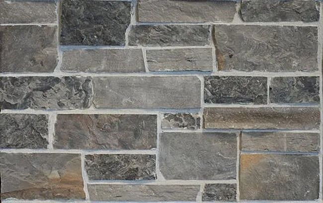 Stone wall, gray and tan, irregular rectangular shapes with white grout.