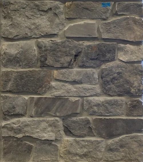 Stone wall, various shades of gray and tan, with rough texture and mortar.