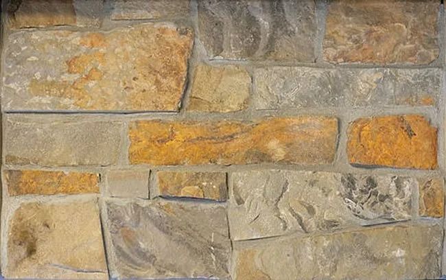 Stone wall with varied rectangular shapes in tan, gray, and gold hues.
