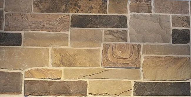 Stone wall with varying shades of brown and beige rectangular and square blocks.