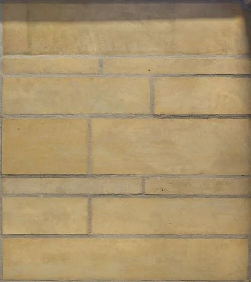Tan rectangular stone wall with gray mortar lines.