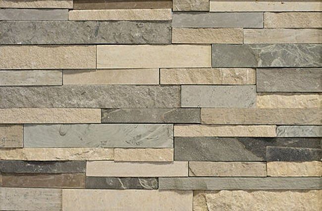 Stone wall with alternating horizontal rectangular pieces in varying shades of beige and gray.