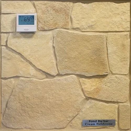 Cream-colored Fond Du Lac Cream Fieldstone tile sample with a thermostat, indoors.