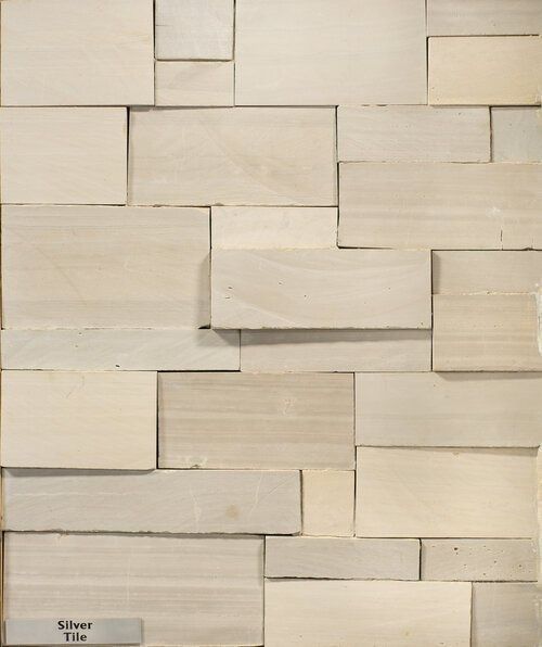Textured silver-colored rectangular tile wall with varying sizes, arranged in a staggered pattern.