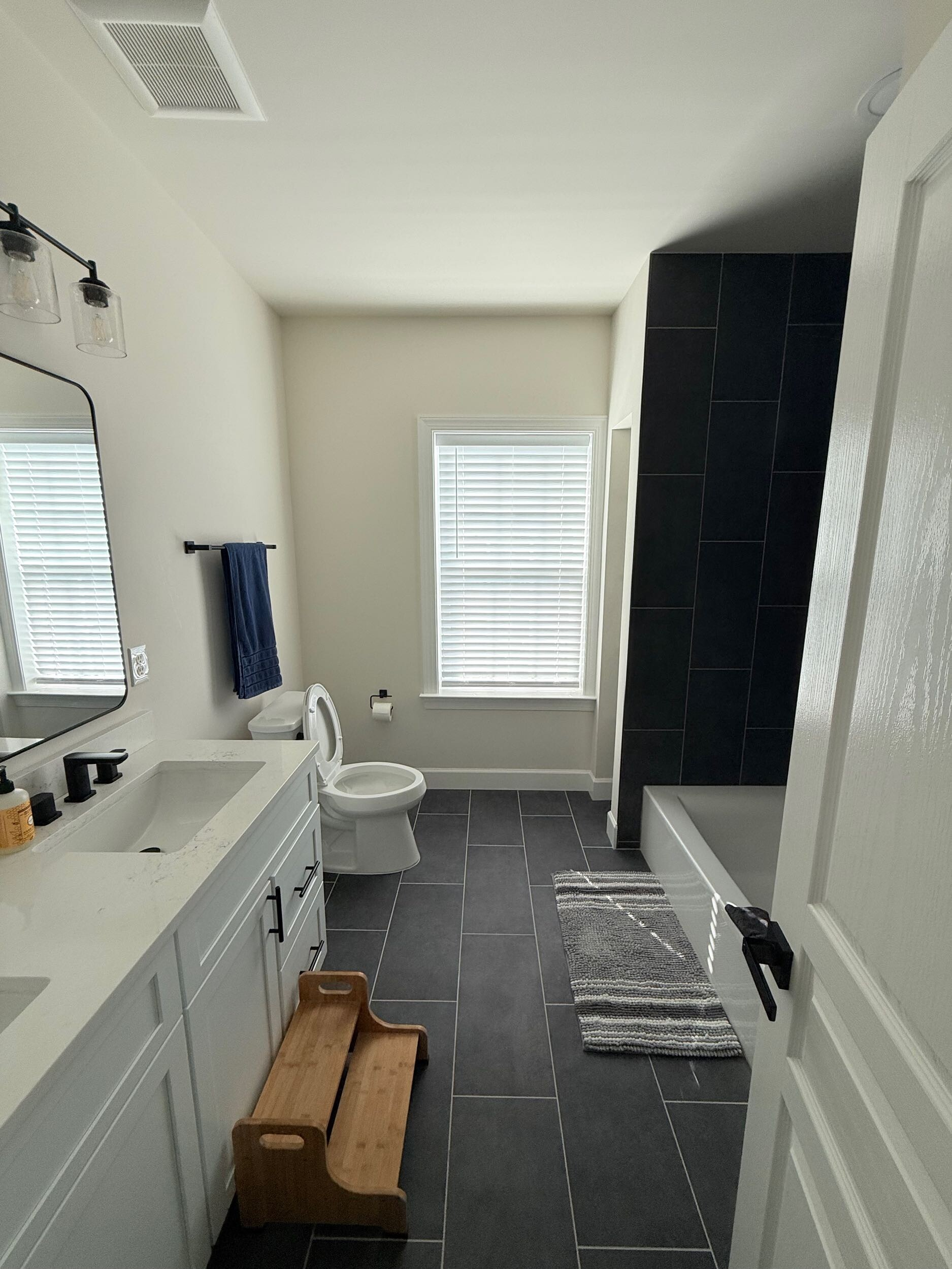 Modern bathroom with dual sinks, wooden-framed mirrors, white countertop, and floating shelves.